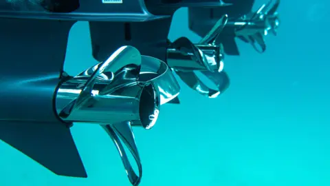 Sharrow Engineering Sharrow Engineering boat propellers underwater. The blades twist back on themselves, almost like a bow.